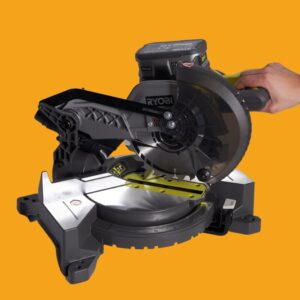 South asian holding mitre saw on yellow background