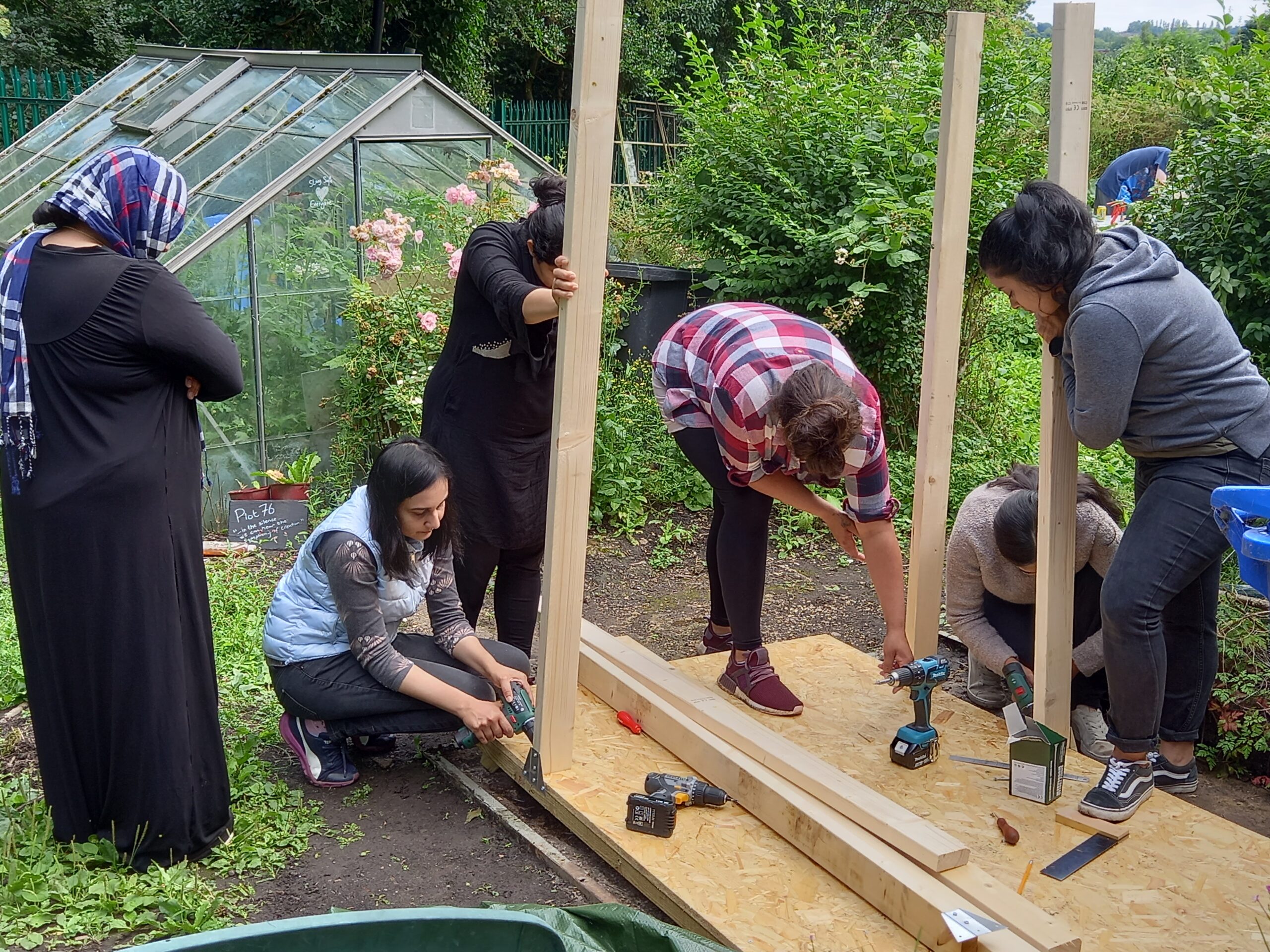 South Asian Women building with wood outside