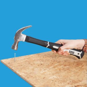 Caucasian female holding hammer and hammering in nail to chip board